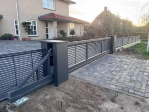 Elektrische schuifpoort bij inrit van een huis met een looppoort