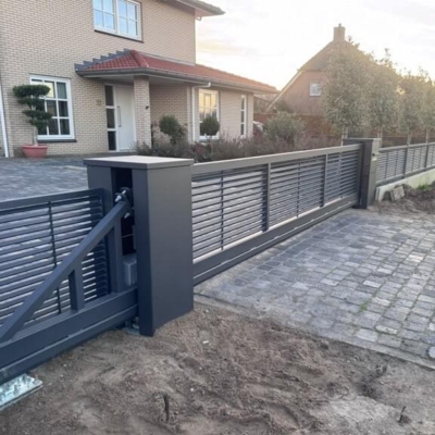 Elektrische schuifpoort bij inrit van een huis met een looppoort