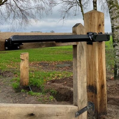 Zwarte Fadini HINDI lineaire poortopener als poortautomatisering bij een houten toegangspoort